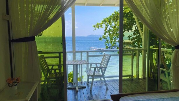 A balcony with a view of the sea, a table, and two chairs. - OYO 90980 Rainbow Island Sepanggar (Sepanggar Island)