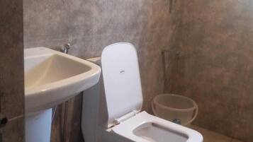 A small bathroom with a toilet, sink, and shower.
