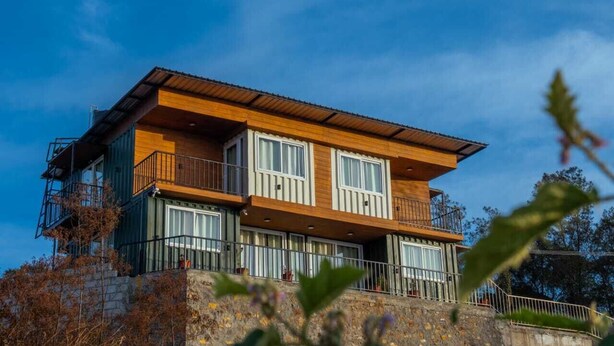 A multi-story building with balconies, large windows, and a stone base. - The Green Cube (Kodaikanal)