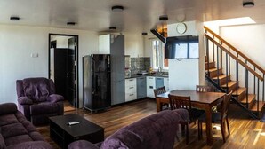 A compact living space with a sofa set, a dining table, and a kitchen area. - The Green Cube (Kodaikanal)