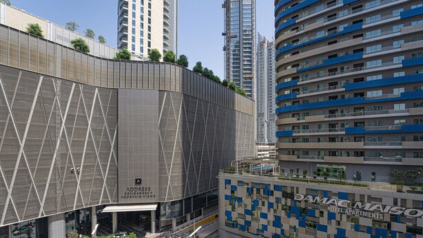 A modern hotel with a unique geometric facade, a rooftop garden, and a view of surrounding high-rise buildings. - Luxe 2BR by Dubai Mall Gym/pool by Belvilla (Dubai)