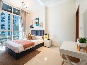 Ein modernes Schlafzimmer mit einem großen Bett, Nachttischen, einem Schreibtisch und Blick auf eine Stadtlandschaft.