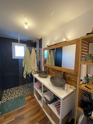 Bathroom features a large mirror, double sink, and wooden shelf.