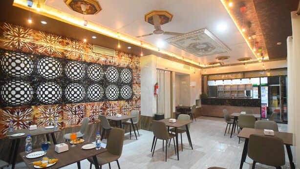 A restaurant with a modern interior, featuring a patterned wall, multiple dining tables, and a bar area.