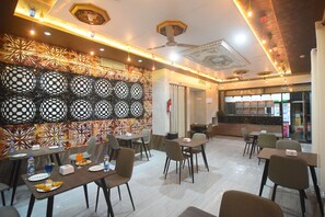 A restaurant with a modern interior, featuring a patterned wall, multiple dining tables, and a bar area. - R Empire Revtree (Davanagere)