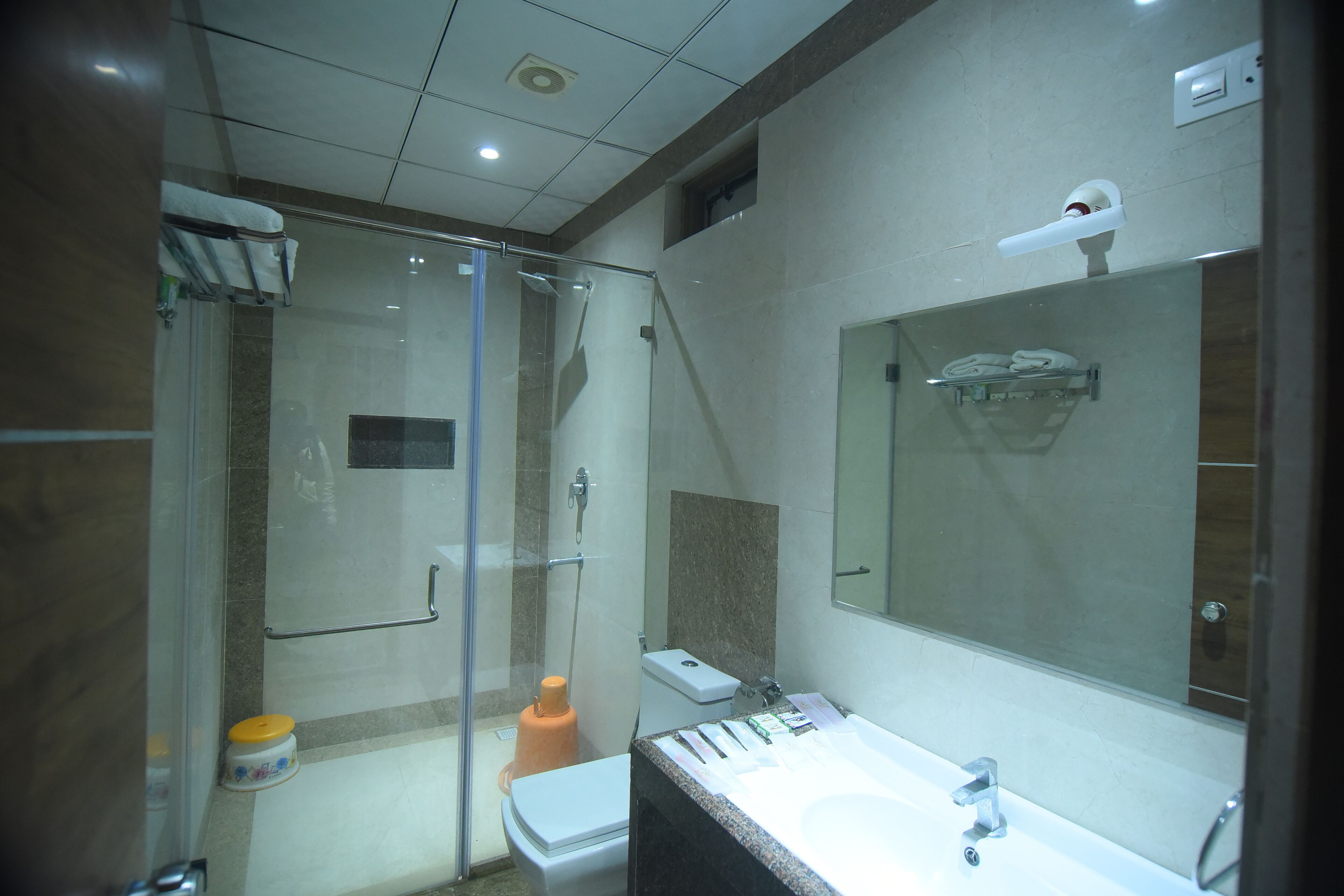 A modern bathroom with a glass shower enclosure, a white toilet, a sink with a mirror, and a towel rack.