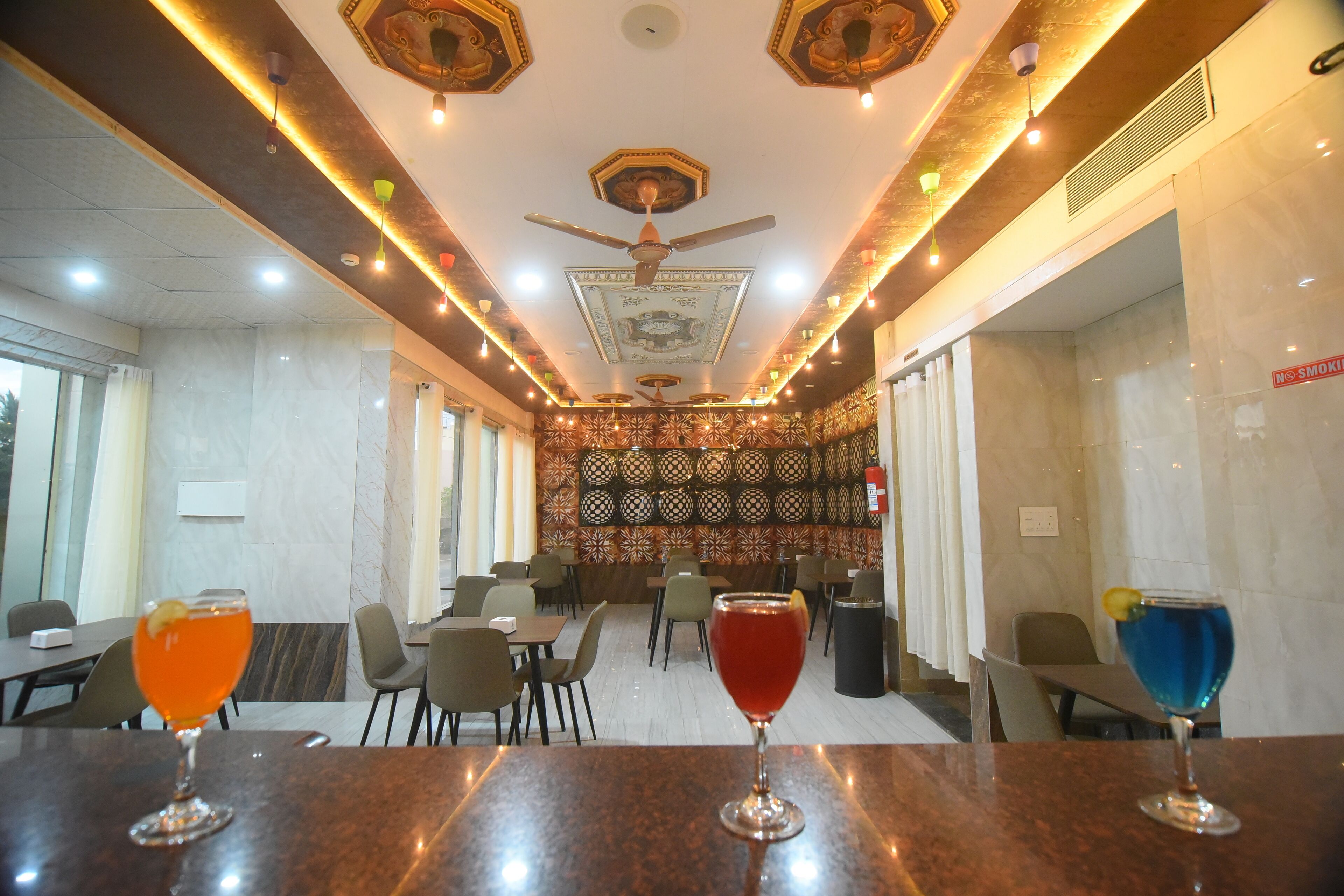 A restaurant with marble walls, ceiling fans, and tables with drinks.