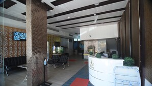 A reception area with a white counter, black chairs, and a red carpet.