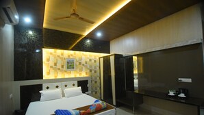 A modern hotel room with a large bed, a desk, and a television.
