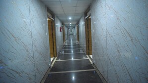 A long, narrow hallway with marble walls and a reflective floor, leading to a door at the end.