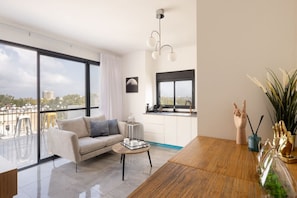 Una sala de estar moderna con un sofá, una mesa de centro y vistas de la ciudad a través de amplios ventanales.