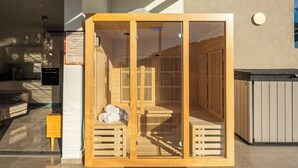 A wooden sauna with a glass door, a small table with towels, and a staircase leading to a higher level. - MAMAD - Bahai Gardens Penthouse by Sea N' Rent (Haifa)
