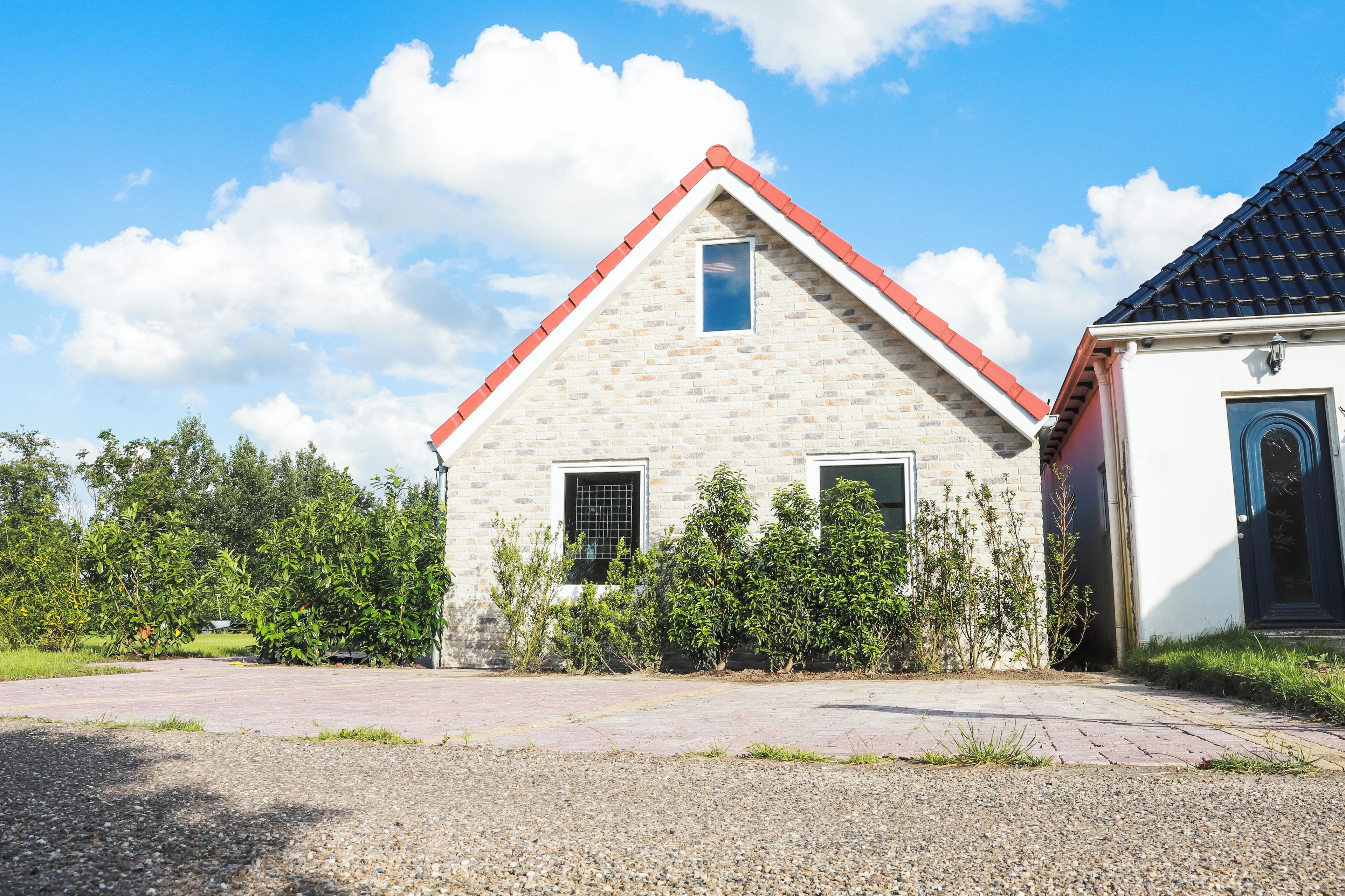 Een gebouw met twee verdiepingen, voorzien van een rode pannendak, een klein raam en een deur.