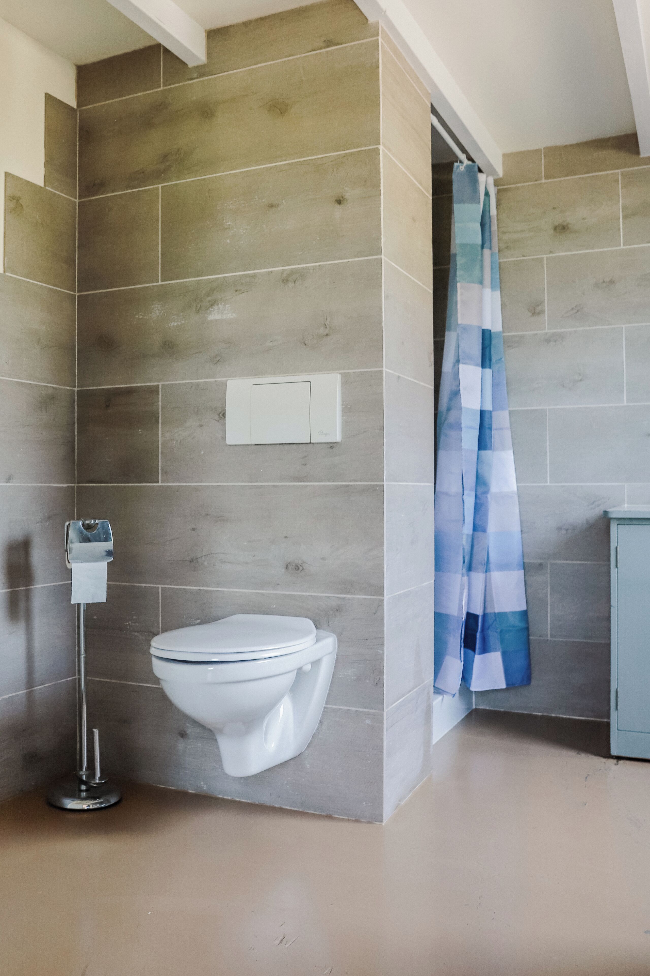 Un baño de diseño moderno, con inodoro, dispensador de toallas de papel y cortina de ducha.