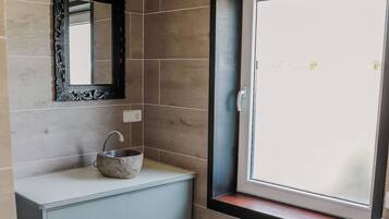 Un baño con un lavamanos de piedra, un espejo, una ventana y una lavadora.