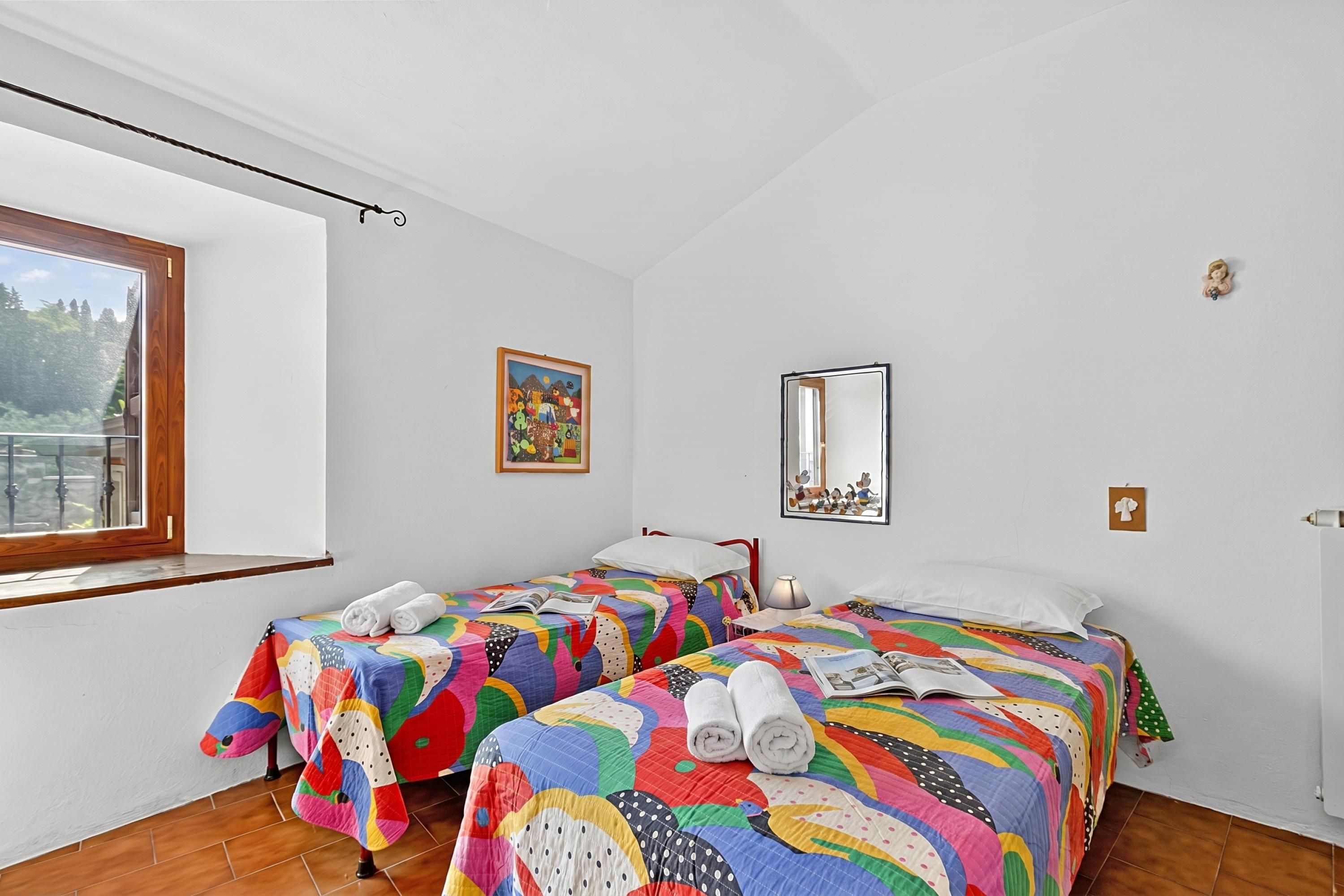 A room with two beds, a window, a painting, and a mirror.