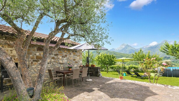 Un edificio in pietra con patio, posti a sedere all'aperto e vista sulle montagne.