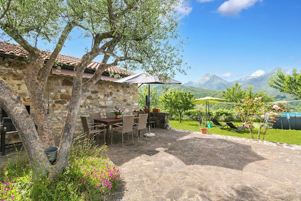Un bĂątiment en pierre dotĂ© dâune terrasse, de siĂšges en plein air et offrant une vue sur la montagne.