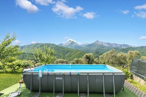 Une piscine hors sol de la marque INTEK, avec une vue sur les montagnes en arriĂšre-plan.