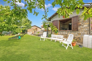 A stone house with a stone wall, a wooden door, and a white bench in the yard. - Casa Sant'anna With Pool - in Garfagnana (Minucciano)