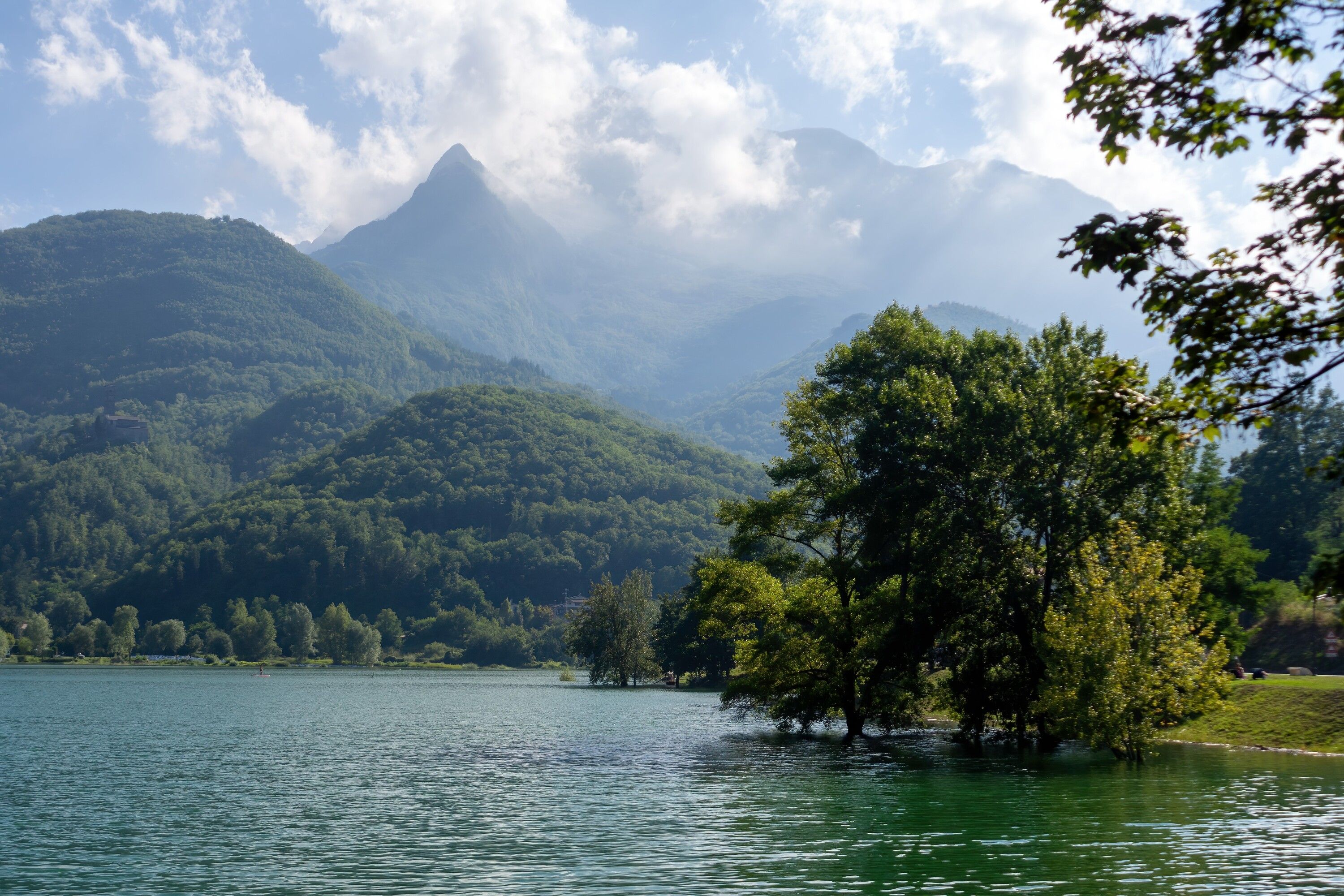 Un lac entouré de montagnes et d’arbres.