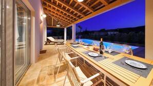 An outdoor dining area with a pool view, wooden ceiling, and glass doors. - Papa's court Mediterranean Pasman Villa with pool II (Pasman)