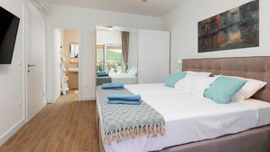 A modern bedroom with a large bed, a ceiling fan, and a view of a bathroom and garden. - Papa's court Mediterranean Pasman Villa with pool II (Pasman)