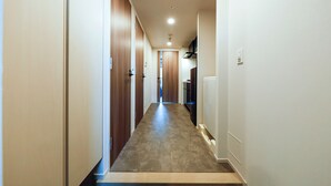Un couloir étroit, avec des portes en bois d’un côté et un mur blanc de l’autre.