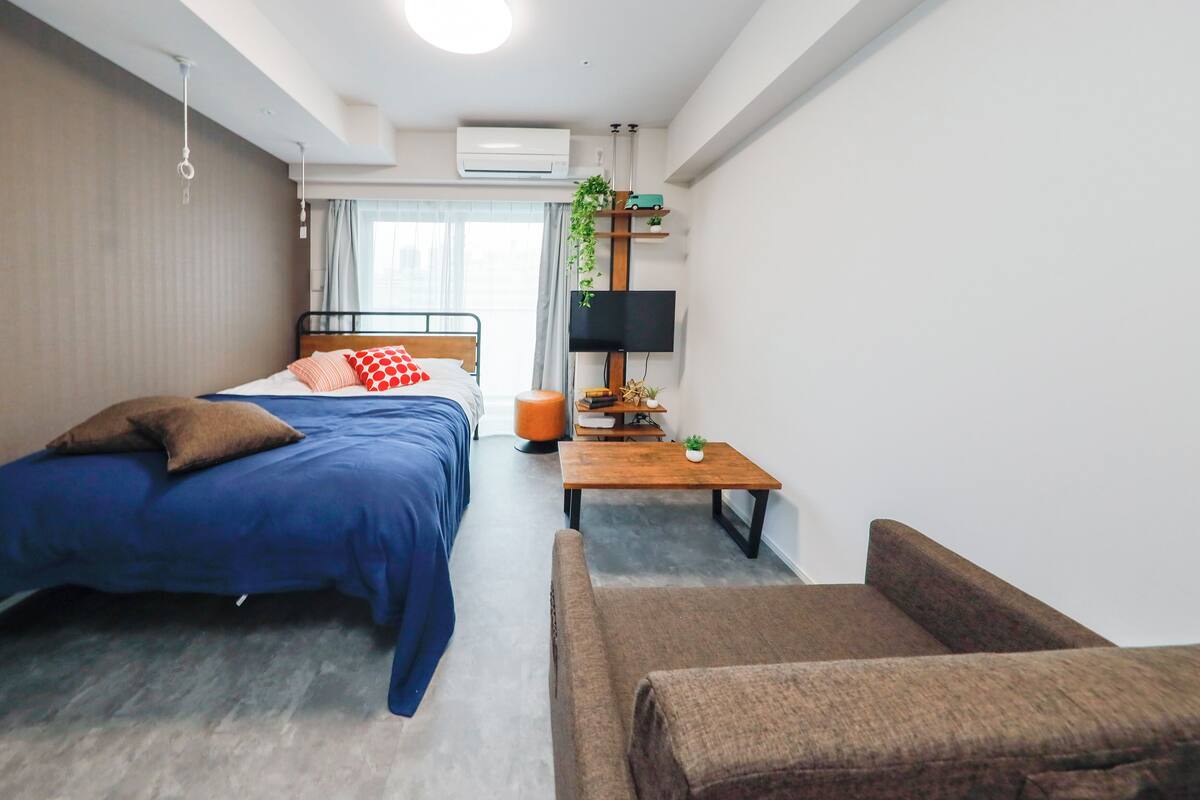 Una habitación de hotel moderna con una cama, un sofá, una mesita y un televisor.