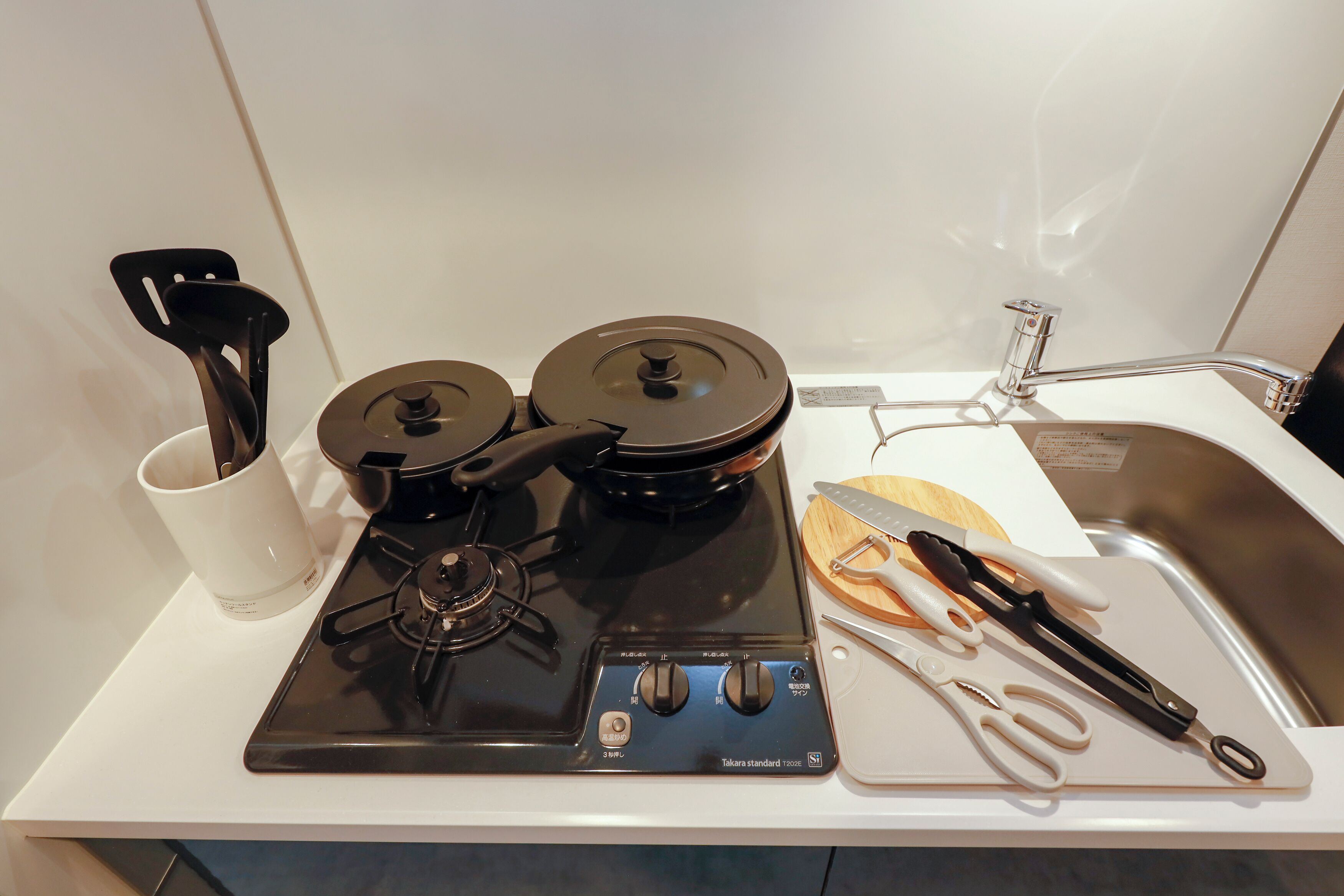 Eine Küche mit Herd, Töpfen, einer Kaffeemaschine und Küchenutensilien.