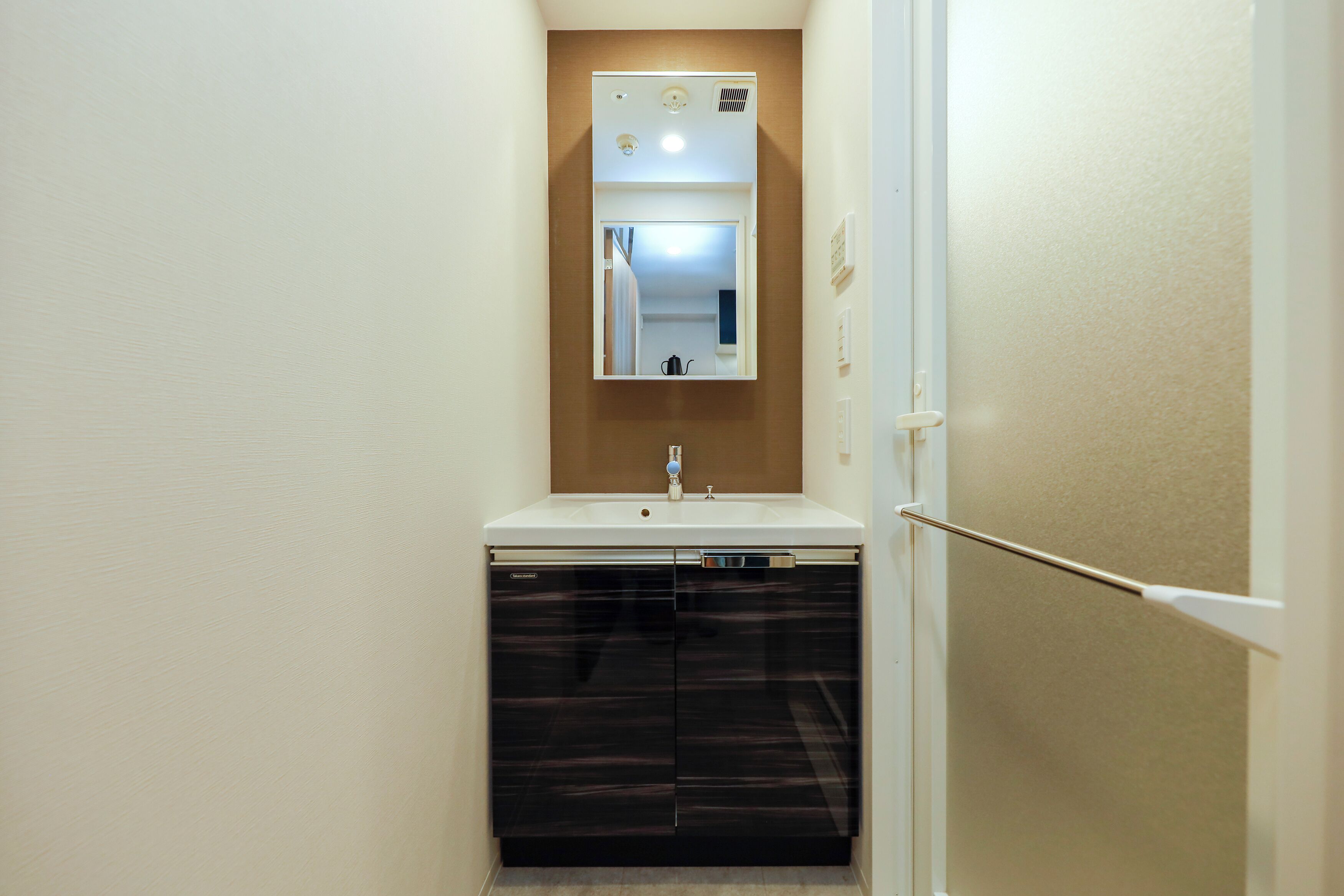 A compact bathroom with a sink, mirror, and dishwasher.