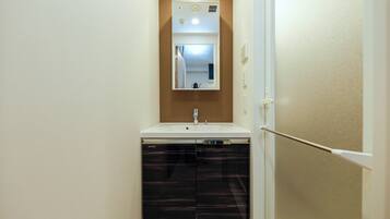 A compact bathroom with a sink, mirror, and dishwasher.