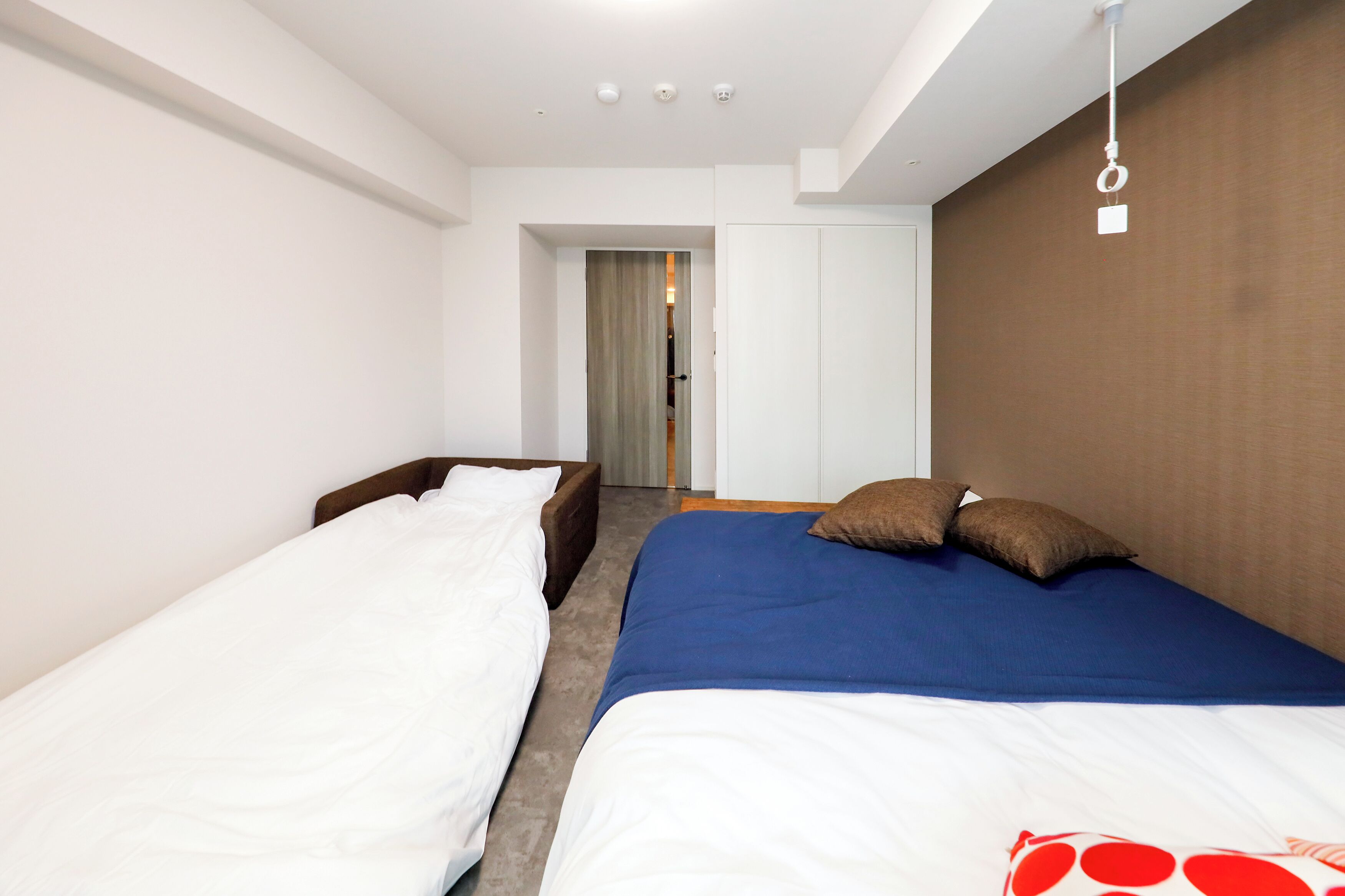 Hotellihuone, jossa on kaksi erillistä sänkyä, puinen pääty, suuri ikkuna ja vaatekaappi.