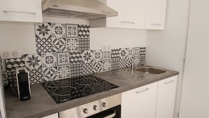 A kitchen with white cabinets, a black stove, and patterned backsplash tiles.