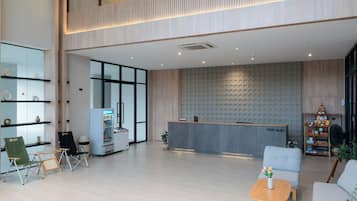 A spacious lobby with a reception desk, seating area, and a wall with circular patterns.