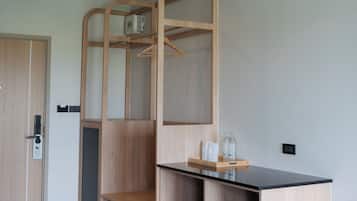 Quarto com armário de madeira, escrivaninha com tampo preto e prateleira suspensa com garrafas.