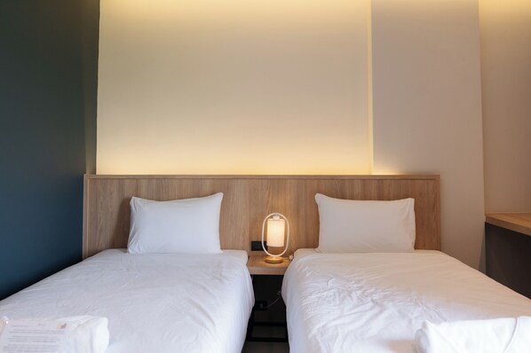A hotel room with two single beds, a wooden headboard, a bedside lamp, and a small nightstand. - The Way Hotel Banpong (Ban Pong)