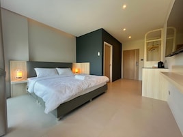 A modern hotel room with a large bed, bedside lamps, a small desk, and a mirror.