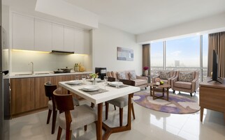 A modern living room with a dining area, a kitchen, and a large window offering a city view.
