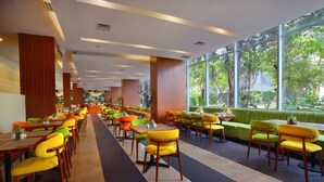 Un restaurant espaiós amb diverses sales de menjador, grans finestres que donen a zones verdes, i diferents opcions de seients, com ara taules i seients privats.