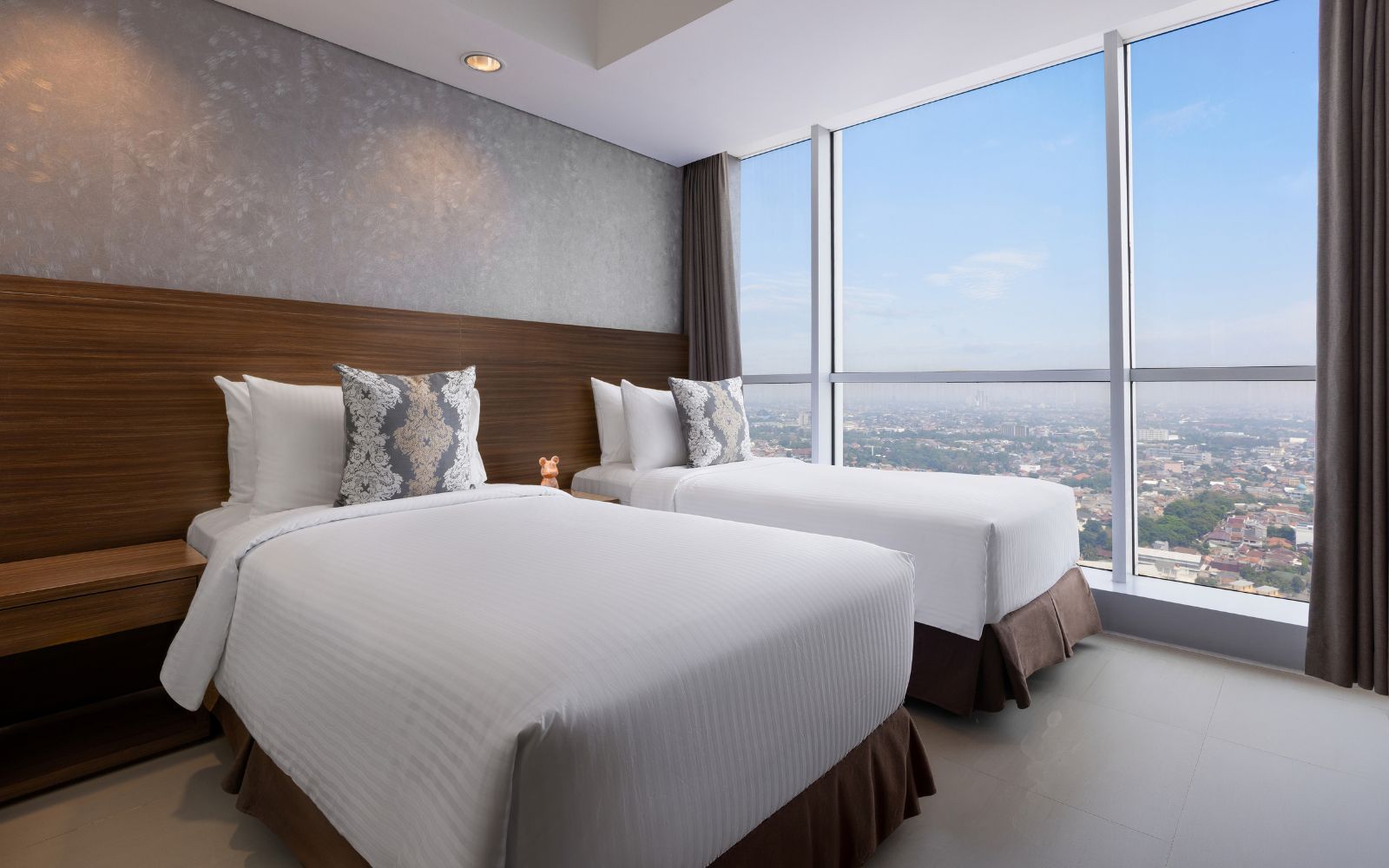 Une chambre d’hôtel avec deux lits, une grande fenêtre et une vue sur la ville.
