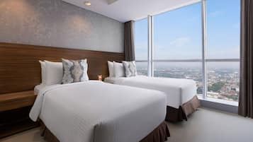 Una habitación de hotel con dos camas, un ventanal grande y vistas a la ciudad.