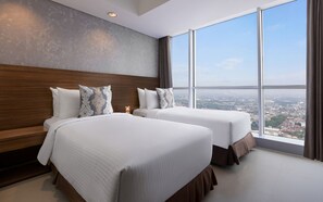 Une chambre d’hôtel avec deux lits, une grande fenêtre et une vue sur la ville.