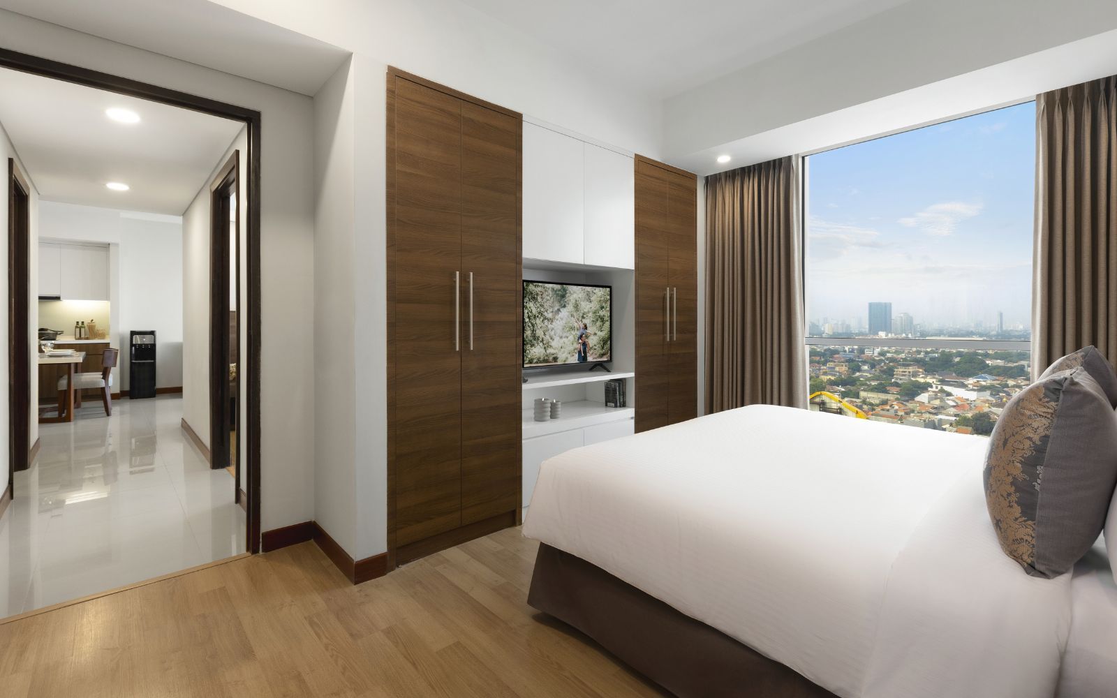 A modern hotel room with a large bed, a TV, and a city view.