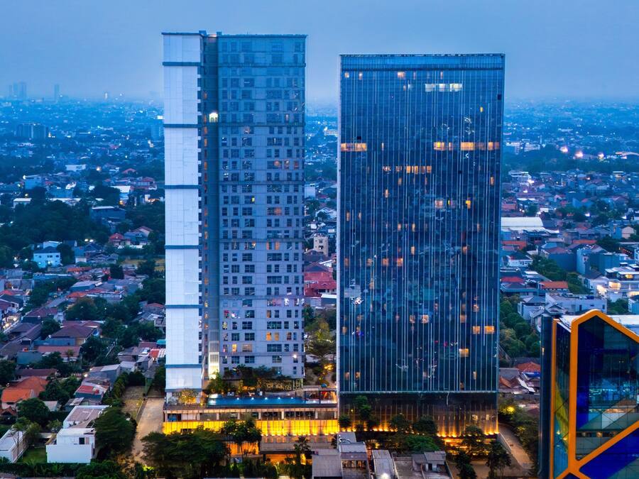 Un edificio de gran altura con varios pisos, rodeado por un paisaje urbano.