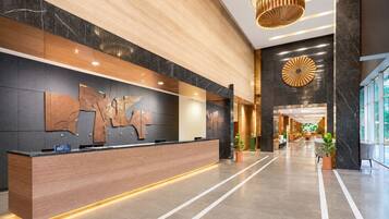 A modern hotel lobby with a reception desk, a large wall art piece, and a circular decorative element on the wall.