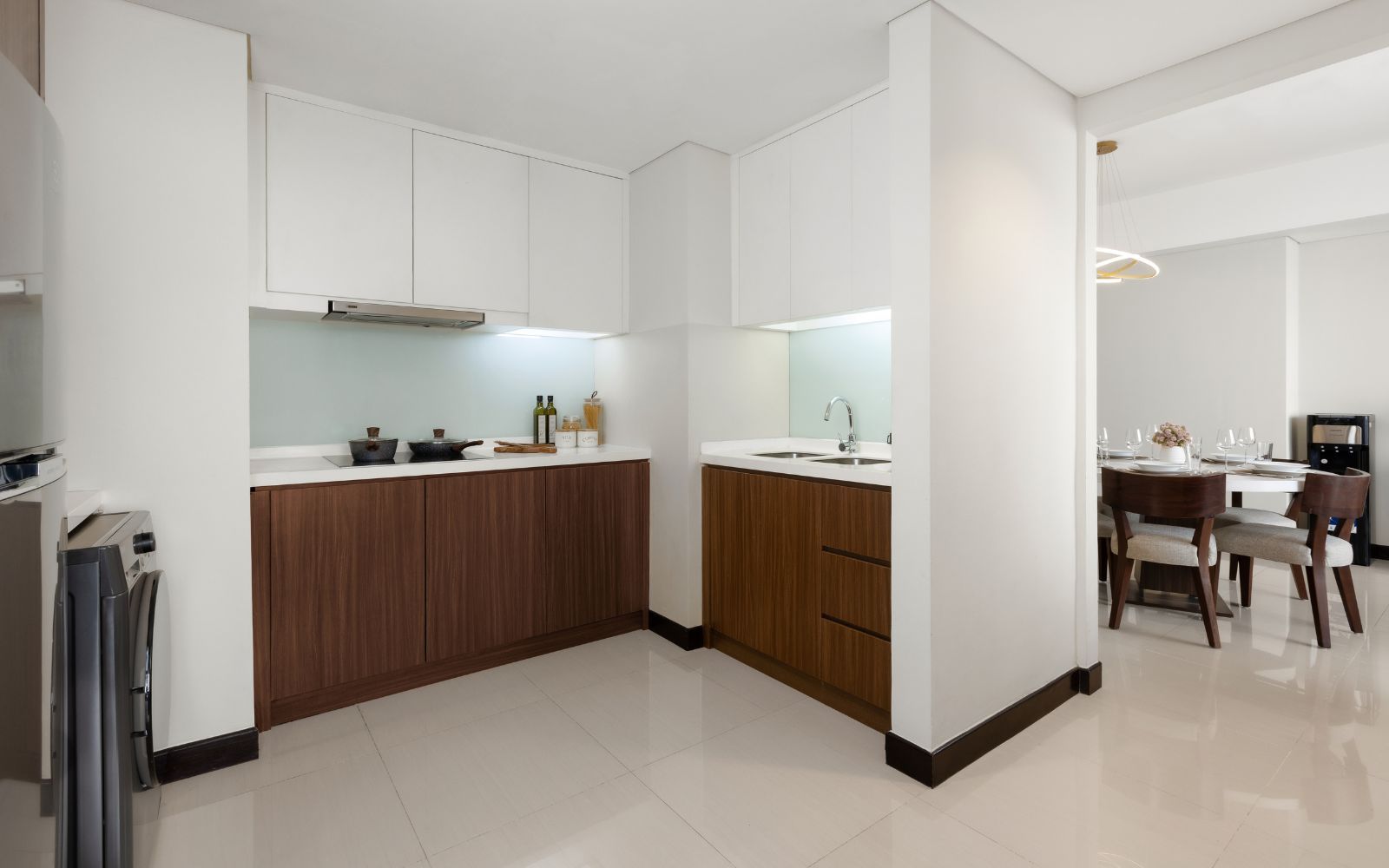 Una cocina moderna con armarios blancos, encimera de madera y comedor con mesa y sillas.