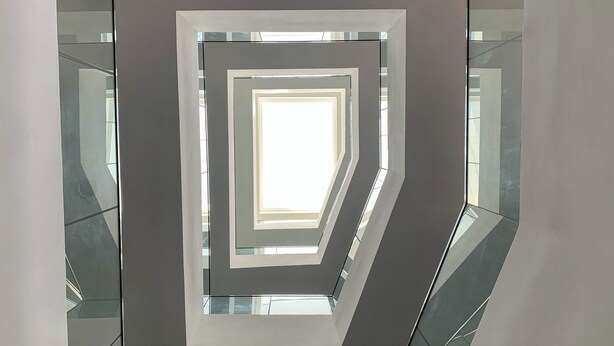 A modern interior with a geometric wall design and reflective surfaces. - MiVi (Lagos)
