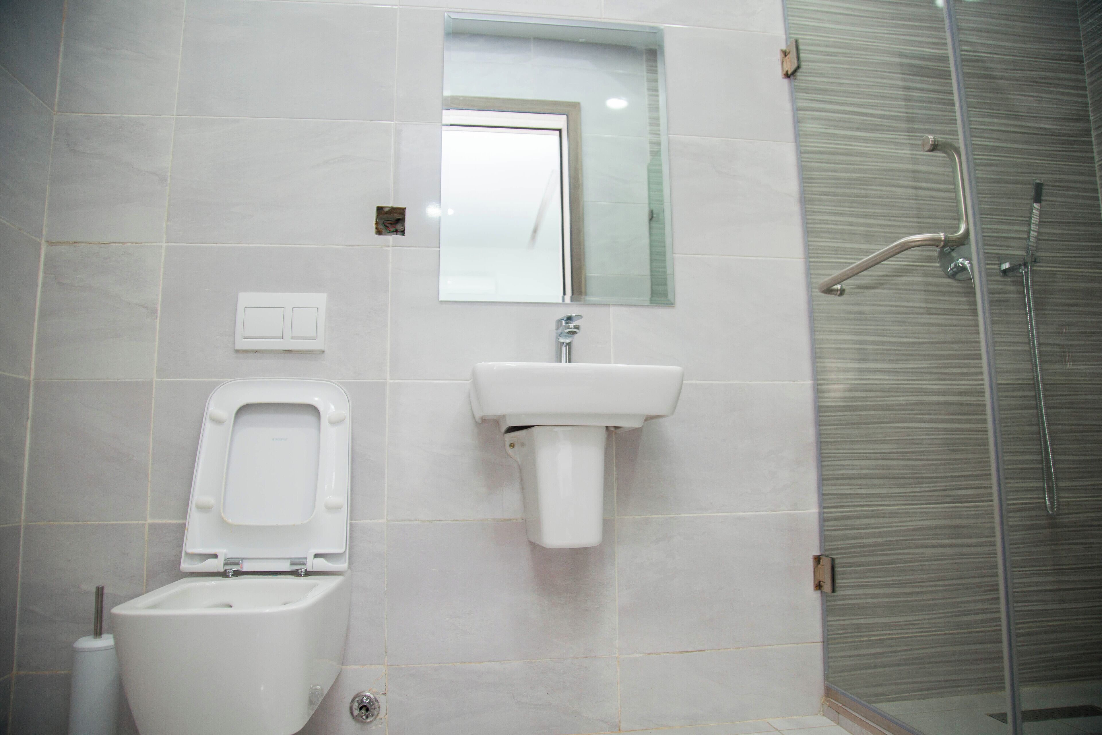 A bathroom with a toilet, sink, and glass shower enclosure.