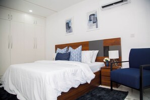 A bedroom with a bed, a nightstand, a chair, and a wardrobe. - MiVi (Lagos)